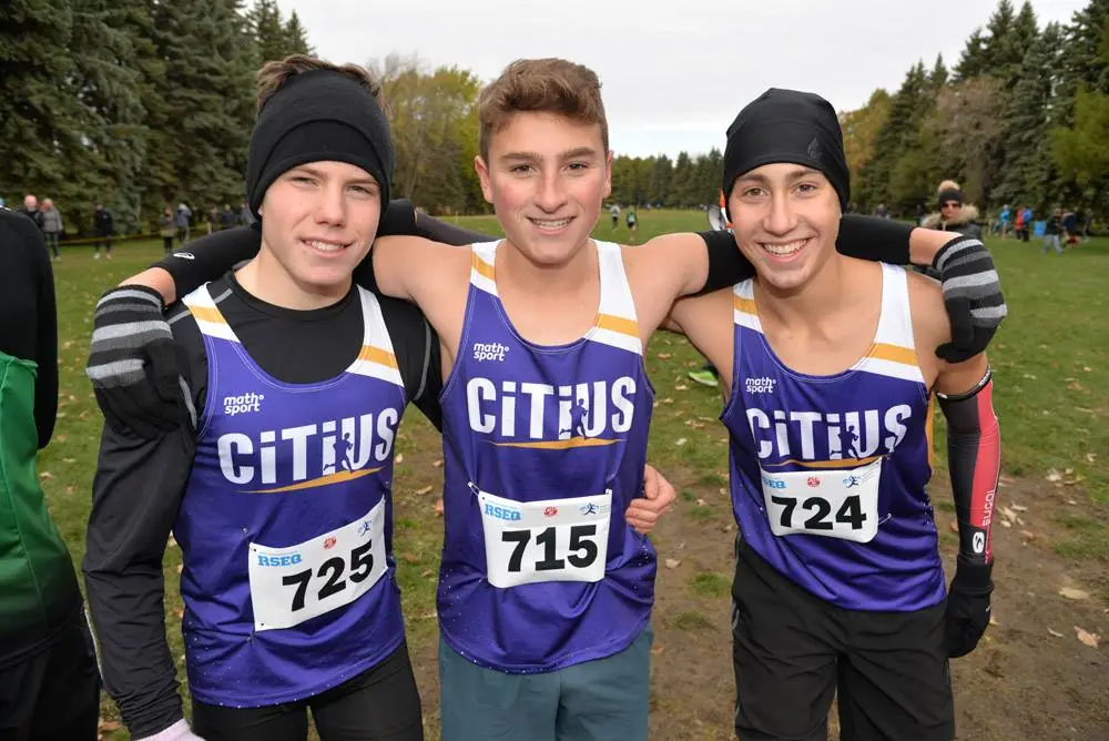 Trois athlètes portent la camisole violette, blanche et or du Club Citius lors d’un cross-country.